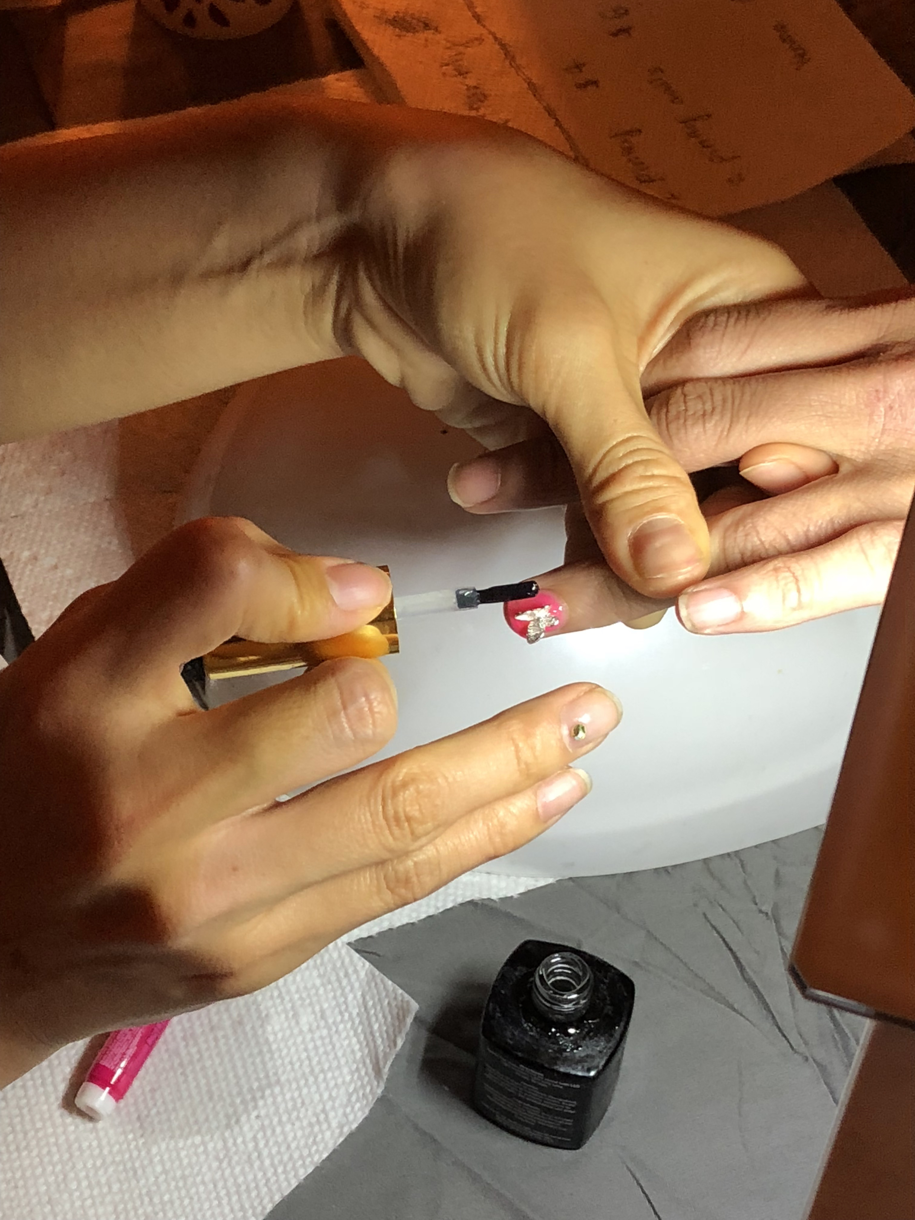 Detail of a woman getting a butterfly charm glued to her nail
